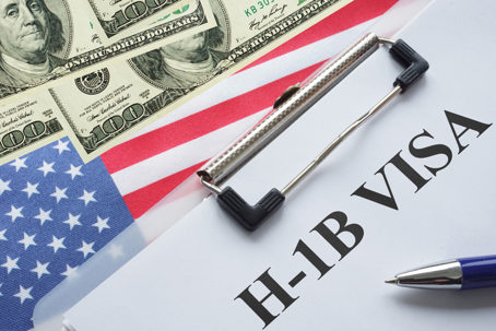 H-1B Visa on paper next to American flag and 100 dollar bills